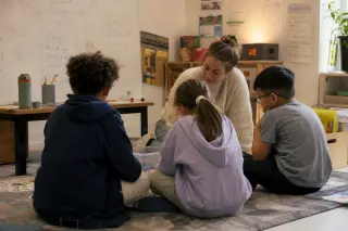 Three diverse students in a classroom corner, deeply engaged in collaborative thinking and mapping ideas, with warm natural lighting and an informal, active atmosphere.